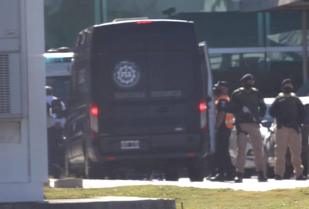 El momento en el que "El Pato" Cabrera (de celeste a la izquierda) va a subir a una traffic policial para ser trasladado a Bouwer desde el Aeropuerto Ambrosio Taravella. Foto exclusiva gentileza